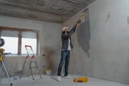 Pintor aplicando pintura en una pared interior